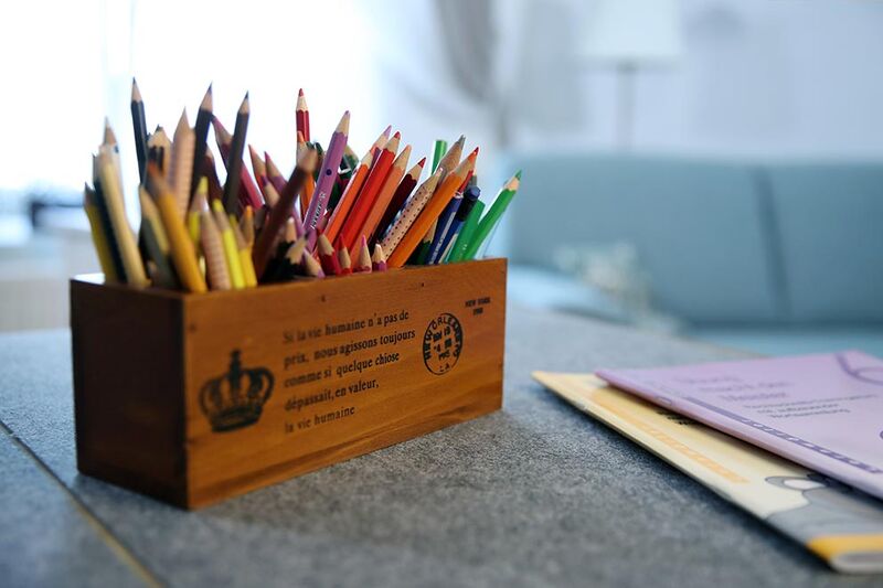 Stifte, Farben, Möglichkeiten. In einer Umgebung, die zum Lernen einlädt, fällt vieles leichter. Buntstifte in Holzbox und Lernmaterial auf einem Tisch – einladender Lernraum